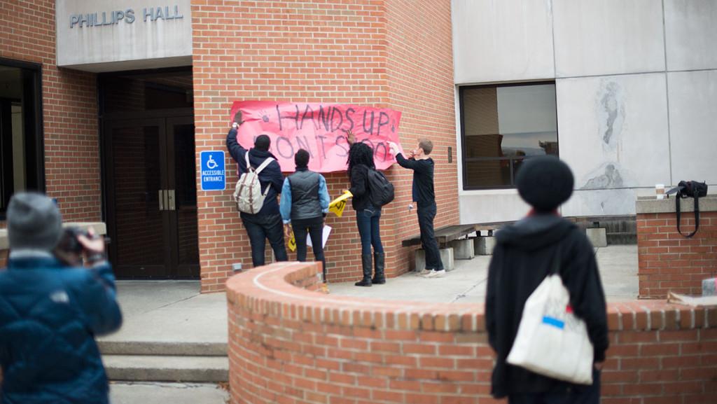 Tommy Battistelli/ The Ithacan  From left, Kobby, senior Kayla Young, senior Crystal Kayiza and sophomore Vin Manta hang up a sign at the Hands Up Walk Out demonstration Dec. 1, 2014. The demonstration was part of a nation-wide solidarity protest in honor of victims of police brutality.