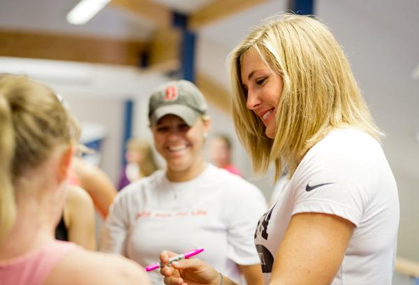 Gold medalist Megan Musnicki ’05 poses for the camera with the women's alumni eight during her visit to Ithaca's Ward Romer Boathouse on Sept. 8.