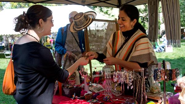 Alba Betancourt-Trompa shows merchandise from Colombia to Ithaca College junior Becky Kabel at the First Peoples Festival Saturday at Dewitt Park.