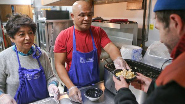 Felix Ramat, a volunteer at the Salvation Army, hands Brian Brigs, an Ithaca resident, a meal Sunday afternoon at the organization’s soup kitchen.