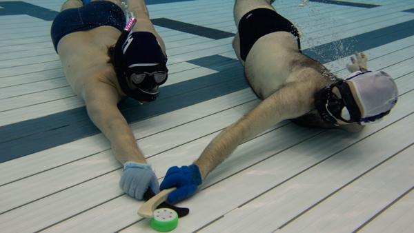 From left, Ithaca Underwater Hockey members Alessandro Farsi and Reid Davis battle for a puck Monday on the bottom of the Athletics and Events center pool in an underwater hockey practice.