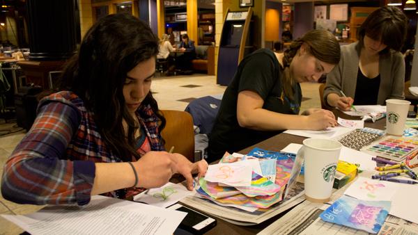 From left, senior Jess Wunsch and junior Moriah Petty paint with watercolors for the Bomber Bike Initiative, one of 10 groups that had a table at the IC Water Week event Tuesday in IC Square.
