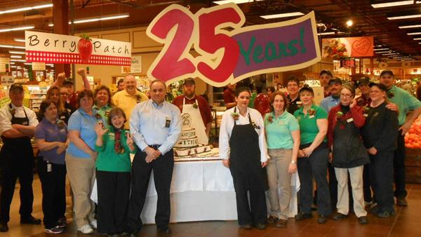 Employees from the Wegmans grocery store in Ithaca stand by a cake they served to customers at the store March 16. The Ithaca location is celebrating its 25th anniversary this year. 