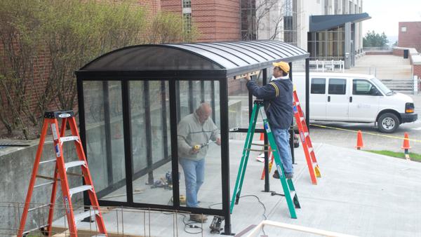From left, Smitty James and Mike Whane work on the Bomber Bikes shelter outside of Williams Hall. Now completed, it holds up to 16 bicycles.