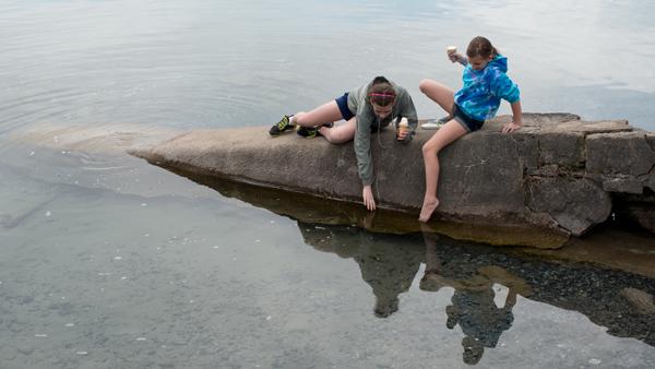 From left, Riley Broyan, 11, and Grace Kush, 10, both of Skaneateles, sit on a rock on Skaneateles Lake. 