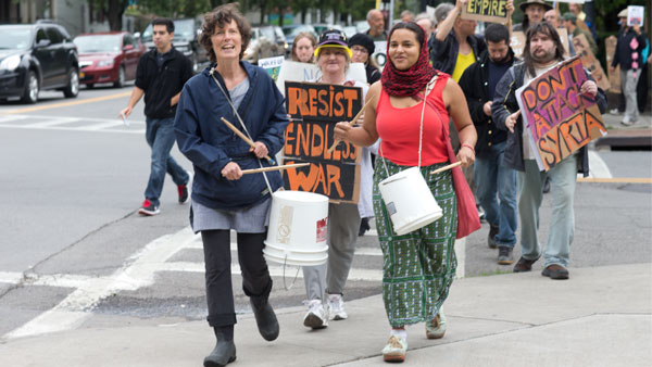 From left, Ithaca residents Claire Grady and Shakti Moksha march down Cayuga Street as a part of an anti war protest on Friday.
