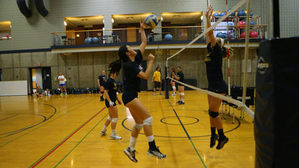 Senior captain Syline Kim attempts to return the ball over the net, while Siobhan Sorenson, freshman outside hitter and middle back, goes up for a block during a practice at the Fitness Center. 