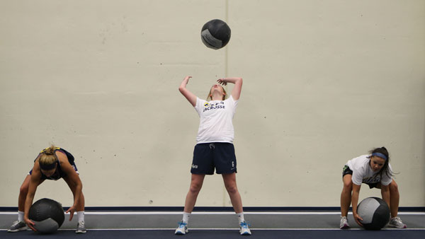 Members of the womens lacrosse team toss a medicine ball in the air as part of a group exercise in Glazer Arena.