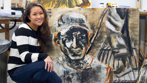 Senior Stephanie Lee poses with her painting Jan. 27 in a studio in Ceracche Center. Her pieces are made of newspaper and tar.
