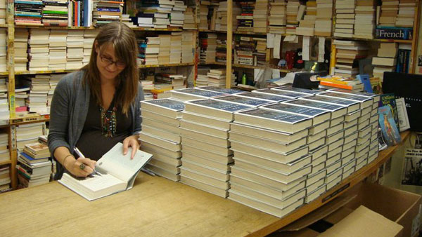 Eleanor Henderson, assistant professor of writing, signs first-edition copies of her book “Ten Thousand Saints” in June of 2011 at the Harvard Book Store’s Signed First Edition Club. Henderson’s book is currently being turned into a film.