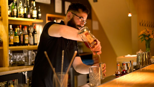 Bartender Manny carefully crafts a cocktail while behind the bar at Mercato Bar and Kitchen on North Aurora St.