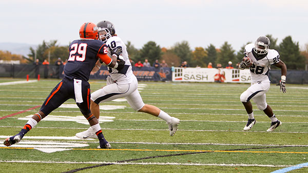 From left, senior wide receiver Matt Pinzka blocks a Utica College defender while running back Rakim Jones 14 carries the ball during the Bombers 26–21 win over the Pioneers on Oct 19, 2013, in Utica, New York. 