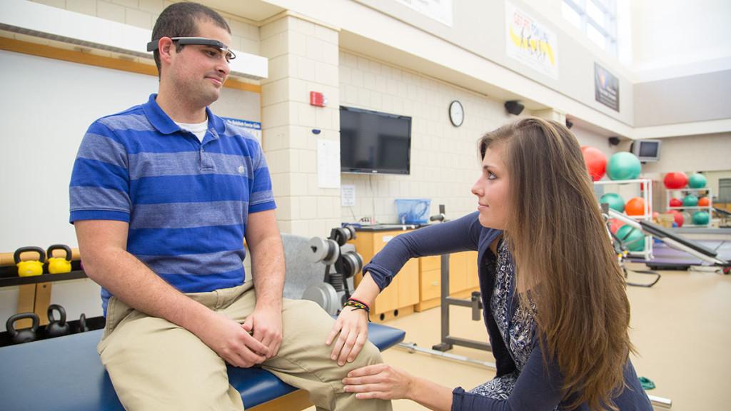 Junior Alex Blackman, left, uses Google Glass to video record junior Fiona Mancuso, right, as she treats him in the physical therapy clinic in the Center for Health Sciences under the supervision of associate professor Michael Buck.