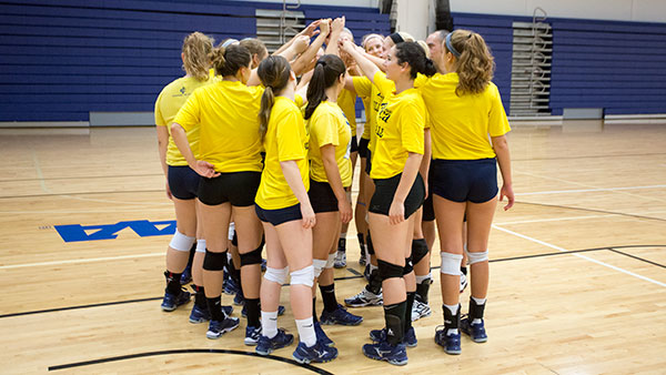 Members of the volleyball team huddle up during the Bombers’ practice on Aug. 20 at Ben Light Gymnasium. The team is 3–0 to begin the season. 