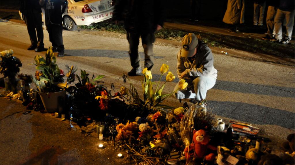 A Ferguson October participant kneels at a memorial dedicated to  Michael Brown on Canfield Drive in Ferguson, Missouri, where he was shot and killed.