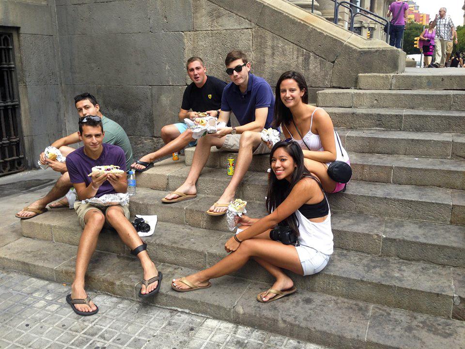 Ithaca College junior Caleb Grant, bottom left, eats with a group of friends on the steps at Placa dAntonio Lopez near the Barceloneta beach in Barcelona, Spain, during his study abroad session for the fall of 2014.