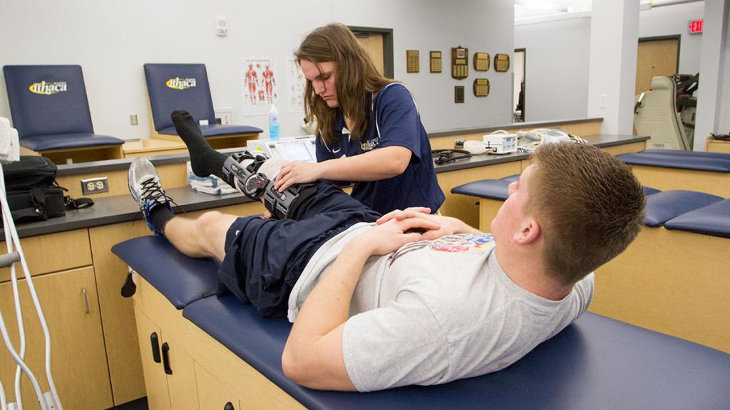 Senior Meaghan Goodheart puts a brace on sophomore wrestler Matt Booth’s knee Dec. 8 in the athletic training room at Hill Center. 