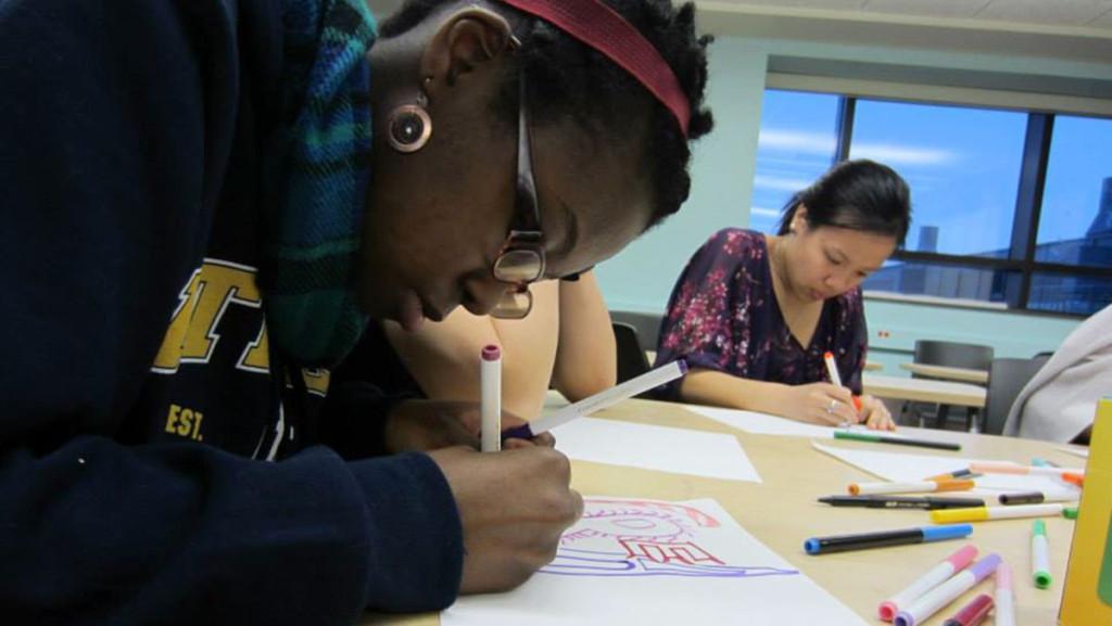 From left, senior Ritza Francois and junior Jacqueline Unger experiment with typography March 4, 2014, during a meeting of Arts Inkorporated.