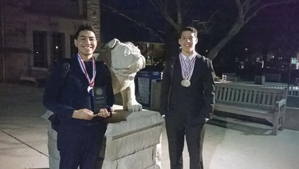 From left, sophomores Jose Escano and Charlie Vaca, who participated in a national debate tournament at Butler University, stand with the mascot.