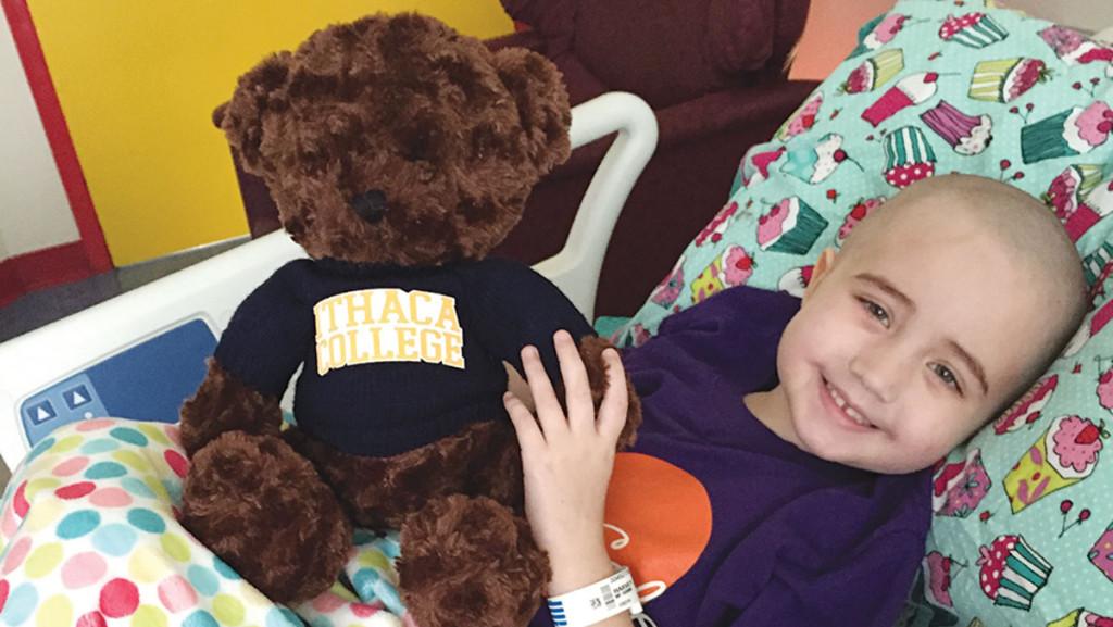 Four-year-old Anya Harvey poses with an Ithaca College teddy bear. The womens lacrosse team has adopted Anya as an honorary member. 
