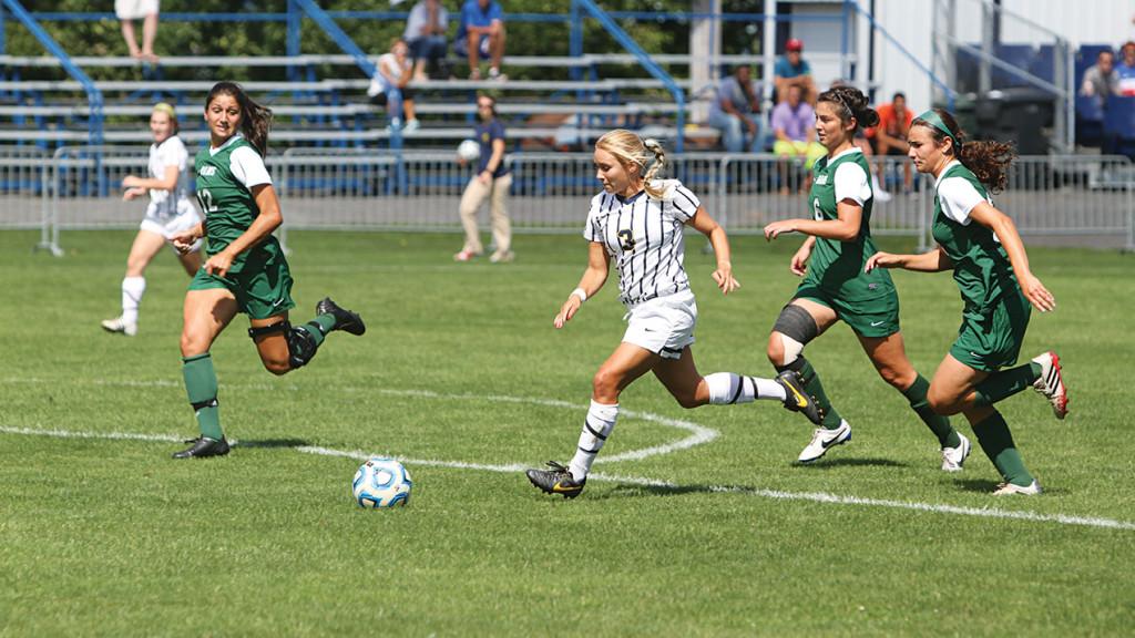 Senior forward Kelsey King dribbles the ball in between two Farmingdale State College defenders during a match against the Rams Sept. 7, 2014, at Carp Wood Field.