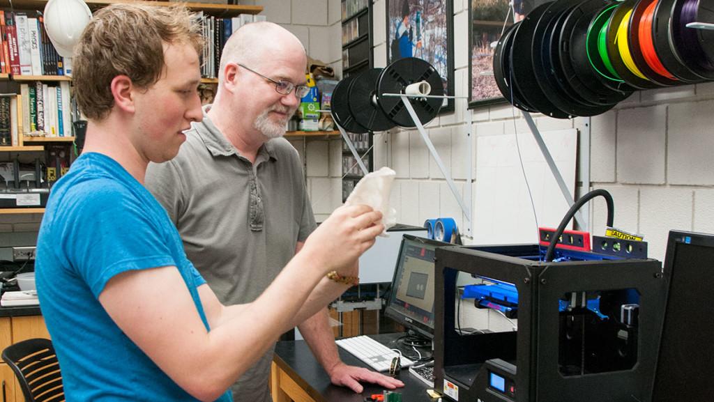 Senior Benjamin Bouricius uses a 3-D printer with Michael “Bodhi” Rogers, professor in the Department of Physics and Astronomy.