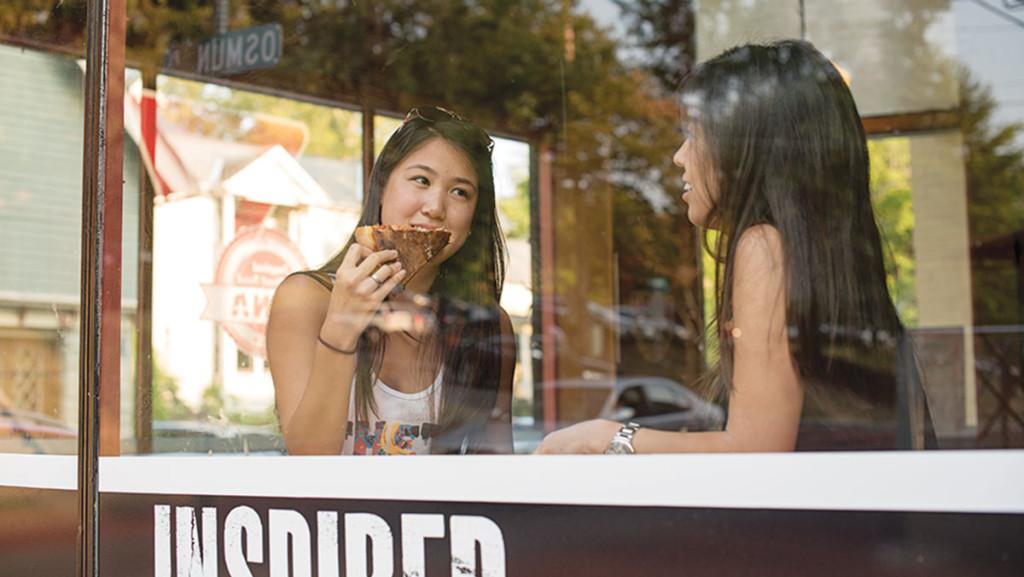 On left, Cornell University student Victoria Li enjoys a slice of pizza at Luna Inspired Street Food, which opened July 21. The interior decorations mimic the inside of a food truck.