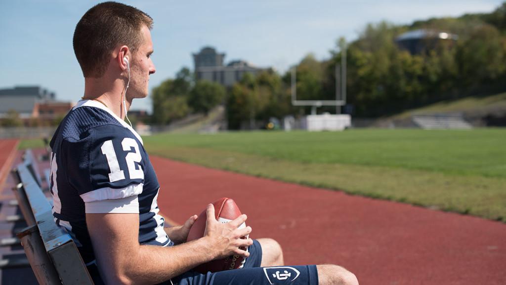 Junior quarterback Wolfgang Shafer sits on a bench Sept. 16 at Butterfield Stadium. After spending the 2014 season as a backup, he has now filled in as the starter for the Bombers football team and looks to lead the squad in 2015. 