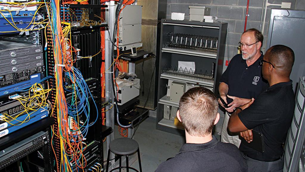William Weeks, Keith McIntosh and Mike Dixon discuss the wireless infrastructure inside a server room in the Park School of Communications. 