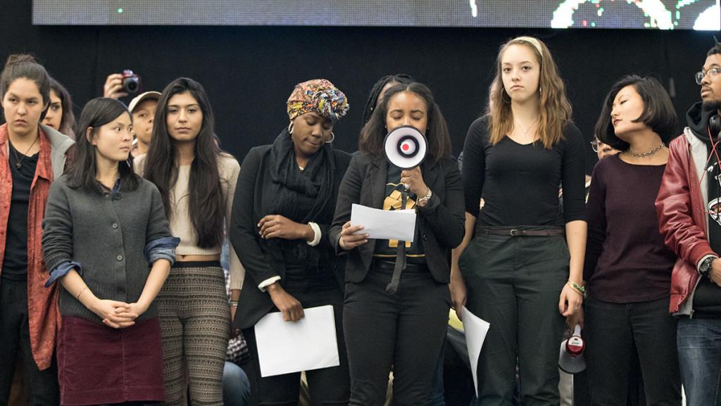 The student group POC at IC and its allies stand on stage and voice their lack of confidence in President Tom Rochon at the “Addressing  Community Action on Racism and Cultural Bias” event Oct. 27. After the demonstration, they walked out of the event amid “no confidence” chants.