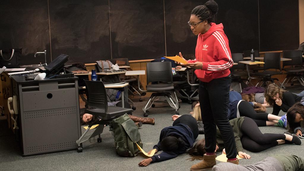 Freshman Kayla Brathwaite reads her spoken-word piece toward the end of the play, with her fellow classmates falling onto the floor around her as she reads her poem.