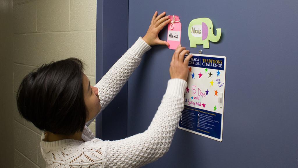 Sophomore “Cathy” Thi Kim Ngan Tran, RA of the 10th floor of West Tower, hangs a nametag on the door. RAs at the college said they are unhappy with the compensation provided.