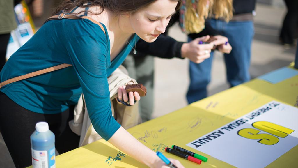 Sophomore Natalie Shanklin signs a poster at a Sexual Harassment and Assault Response and Education event in Fall 2014. Students and administrators at Ithaca College say the college can improve its sexual assault education with more resources and dialogue on-campus.