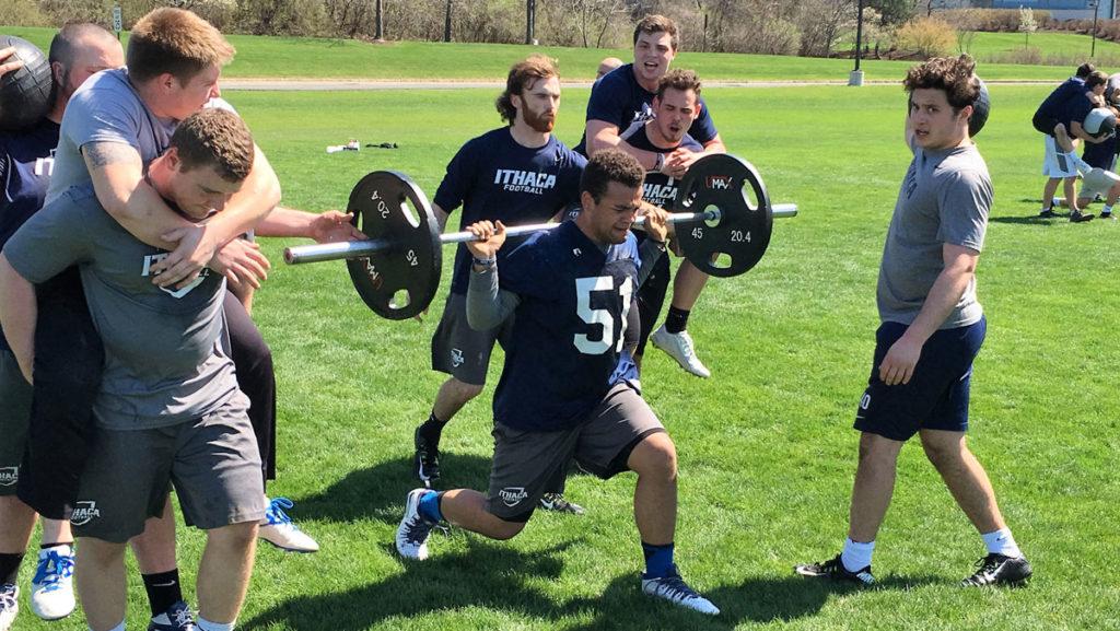 Sophomore Marc Barbieri lunges while carrying a barbell with two 45-pound weights across the field. His brother Rob Barbieri is a senior on the football team and a captain.