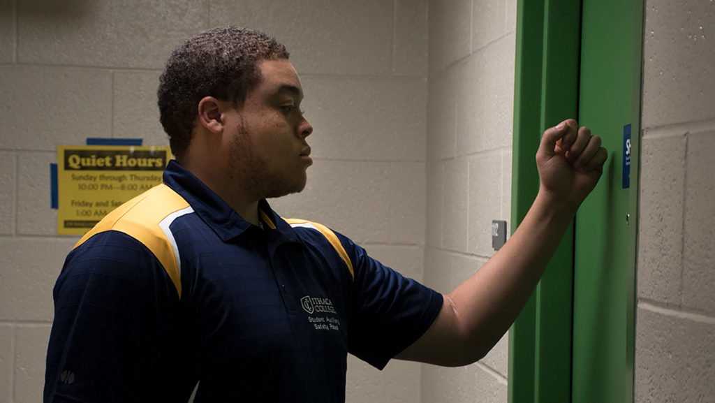 Ithaca College senior, Hakeem Hopper-Collins, executive director of the Student Auxiliary Safety Patrol, knocks on a door as part of his patrol. SASP is a group of 25 students who provide assistance and support to the college’s Office of Public Safety and Emergency Management. 