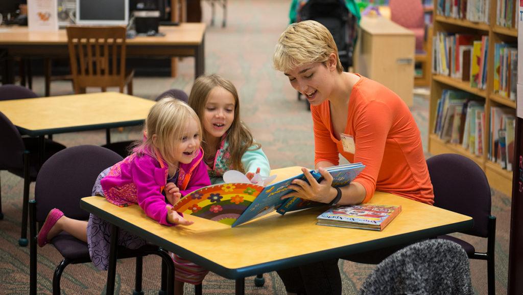 From right to left, Sophomore Anna Gardner reads to 5-year-old Cecilia and her three-year-old sister, Olivia. Nearly every Thursday and Friday Gardner can be found in the childrens section of the Tompkins County Public Library at a miniature desk reading to young kids — just one of many volunteer programs Gardner is a part of.