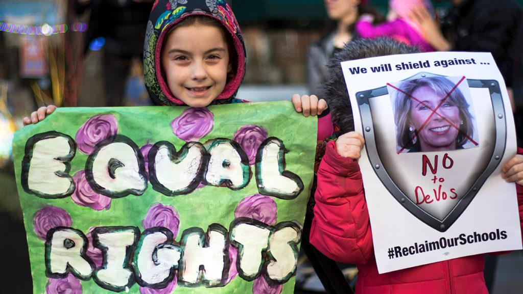 Eight-year-old Lula and 4-year-old Lavinia hold signs advocating for womens rights and opposing the Betsy Devos for education secretary at the Womens March in Ithaca on Jan. 21.