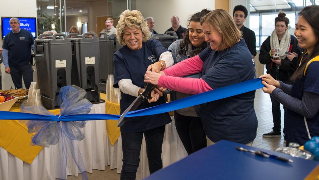 From left, Terri Stewart, director of the Office of Public Safety and Emergency Management, cuts a ribbon with student Monisa Adams and Linda Koenig, assistant director for Housing Services and Communications, to the Public Safety satellite office.
