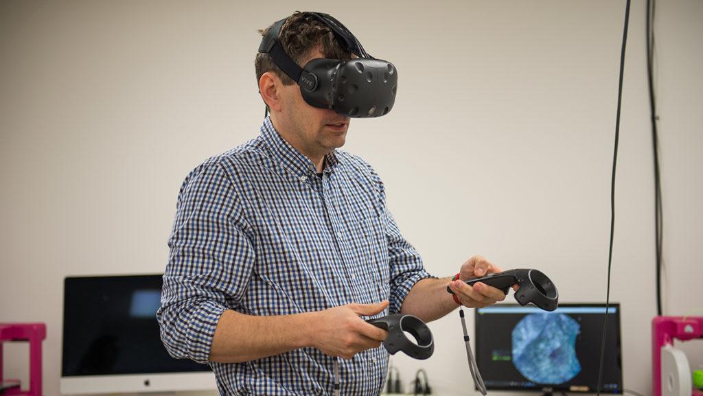 Edward+Schneider%2C+assistant+professor+in+the+Department+of+Strategic+Communication%2C+uses+the+HTC+Vive%2C+a+headset+that+allows+users+to+immerse+themselves+in+virtual+environments+and+interact+freely+within+them.