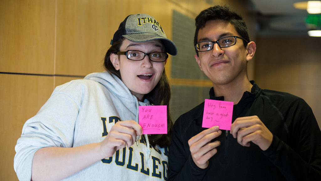 Christina DiLuzio (left) and sophomore Alex Blas (right) hold up post-it notes from their recent campaign to improve student moral during midterm week.