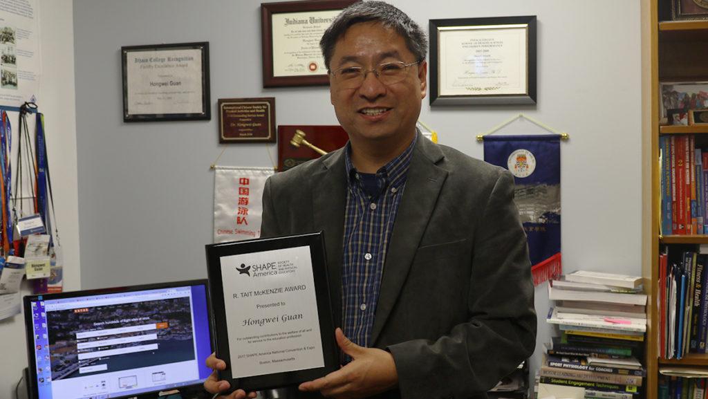 Professor Hongwei Guan holding the R. Tait McKenzie award at his office in Hill Center. He was awarded the award at the SHAPE America conference March 16.