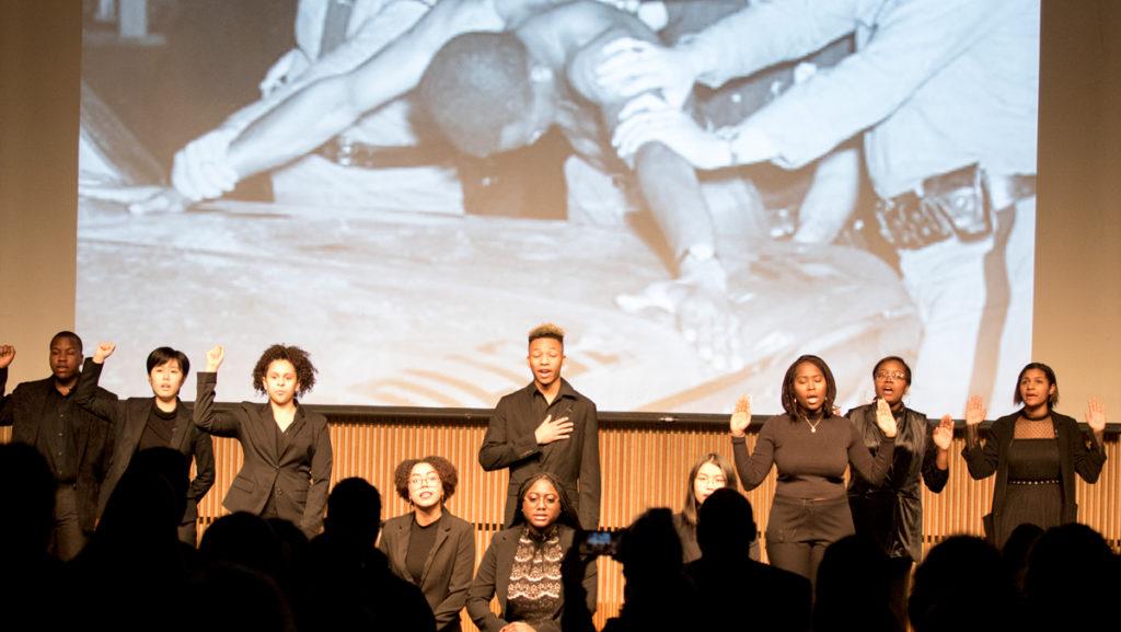  Freshmen MLK Scholars give a presentation of their fall break civil rights tour on Jan. 23 as part of MLK Week 2018. During the national anthem, some scholars kneeled or put a fist up while civil rights photographs played in the background.  						              Caitie Ihrig/The Ithacan