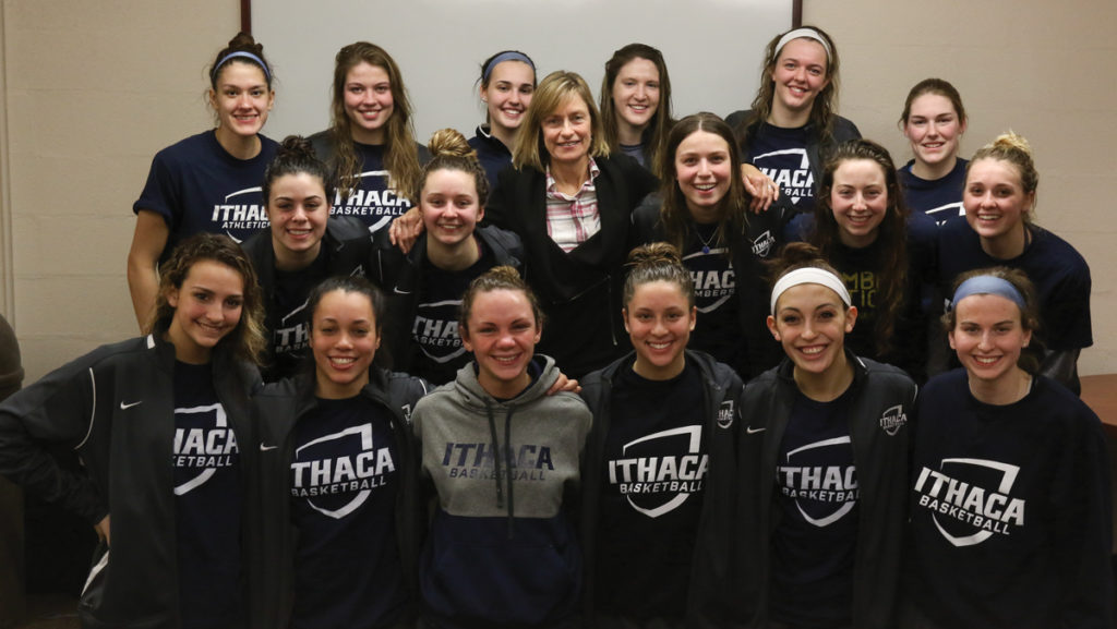 Ithaca College alum Dee Relph stands with the women's basketball team. Relph introduced herself after the team's 71–67 win against the Rochester Institute of Technology.