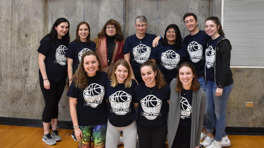 Members of the Ithaca College Chapter of PRSSA stand with Make-A-Wish receipient AnaMaria Ahmed and her mother, Darlene Arnold who were in attendance at the basketball tournament.