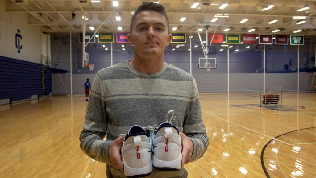 Senior Matt Flood holds up his game sneakers, which have his best friend Zac Garcia’s initials on  them to honor him during Flood’s senior season with the Bombers. Garcia died in a car accident Sept. 9.