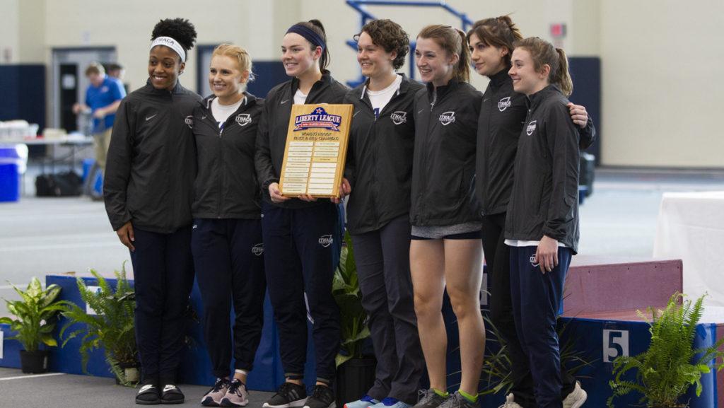 The seniors and captains of the Ithaca College womens track and field team hold the Liberty League first-place plaque after winning the Liberty League Championships with 241.5 points.