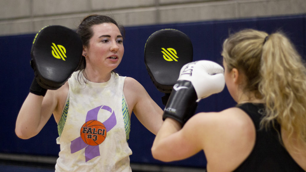 Senior Katherine Siple holds up mitts for senior Valerie Gugliada to practice her punches against during practice in the Fitness Center. Siple is president of the Ithaca College Defenders and a boxing coach.