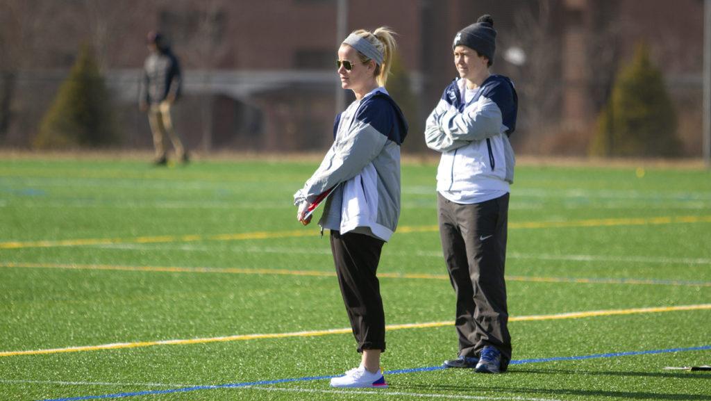 From left, womens lacrosse assistant coach Kayla Minner and head coach Karrie Moore look on as the Blue and Gold face The College at Brockport on March 20.
