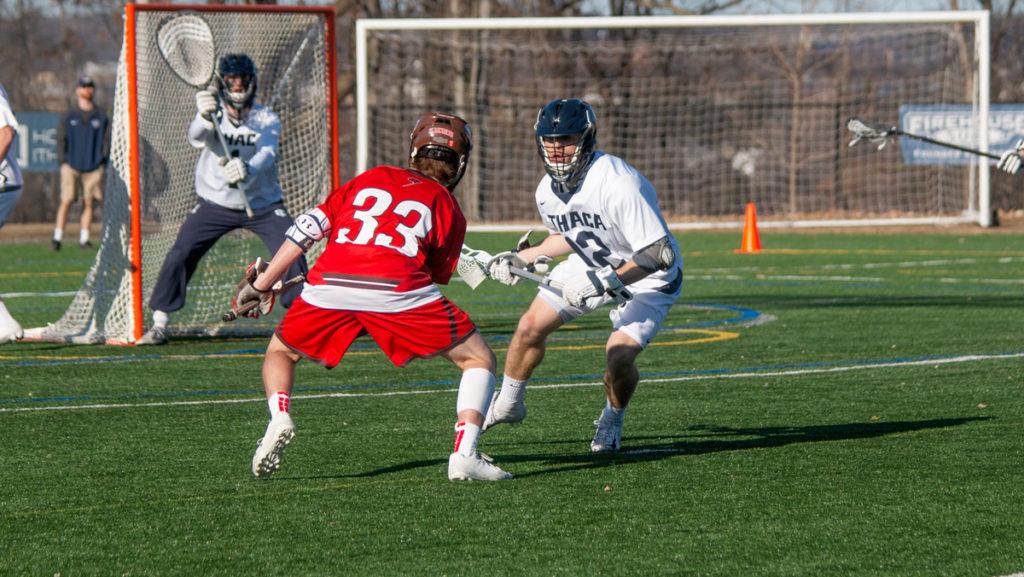 Sophomore midfielder Dillon Fitzpatrick cradles the ball while Saints sophomore midfielder Alex Mapstone looks to steal the ball. The Bombers would win 12–11 in overtime.