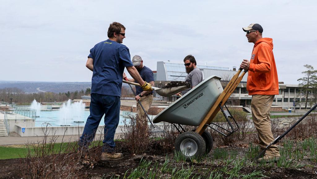 From left, grounds crew members Chris Cornwall, Alex Teeter and Rick Marsh spread mulch in a flower bed near the Dillingham fountains. The crew begins spring landscaping in  March to prepare the campus for Commencement. The grounds crew is also responsible for removing trash, planting flowers and clearing walkways of snow throughout the year.